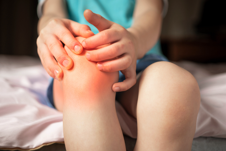 Purchased - Pain in the knee joints of the child. the boy's knees hurt stock photo