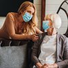 Purchased - Woman interacting with senior citizen in mask