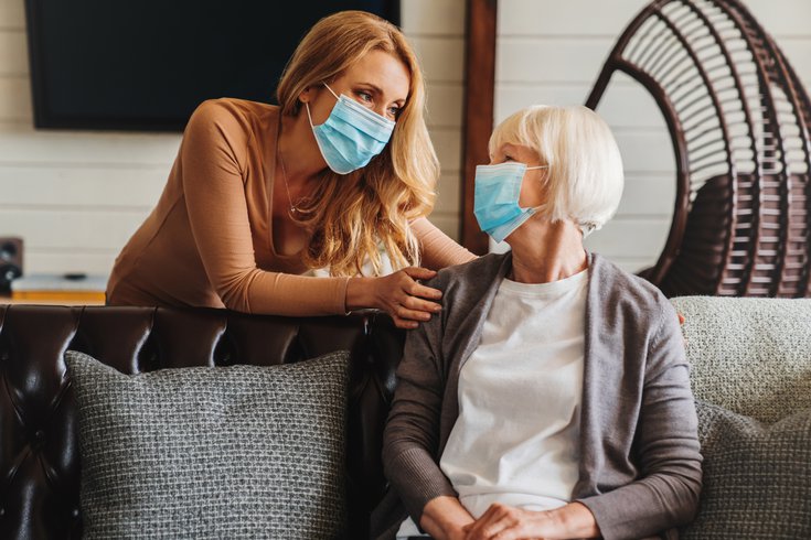 Purchased - Woman interacting with senior citizen in mask