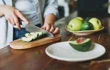 Purchased - Female hands cut avocado on wooden working surface in kitchen at the home stock photo