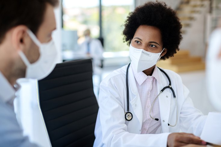 Purchased - Doctor wearing protective face mask while talking to a patient