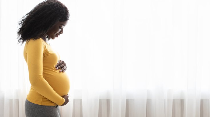 Limited - Pregnant woman looking down at her belly