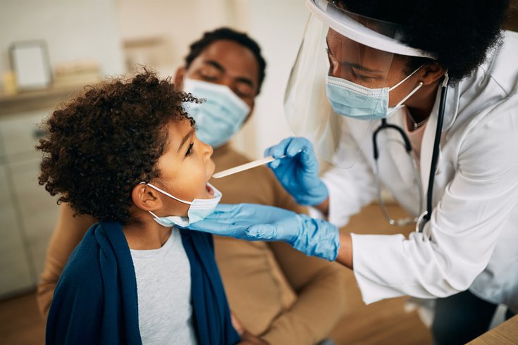 Purchased - doctor with face mask examining boy's throat during a health visit