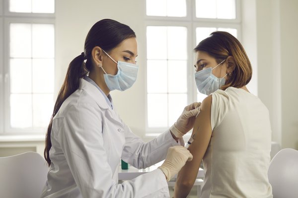 Purchased - Young woman in face mask getting an antiviral vaccine at the hospital