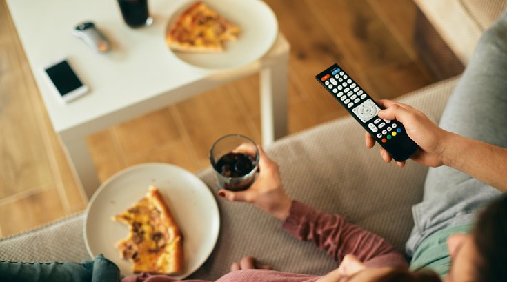 Purchased - Close-up of couple watching TV while eating pizza at home
