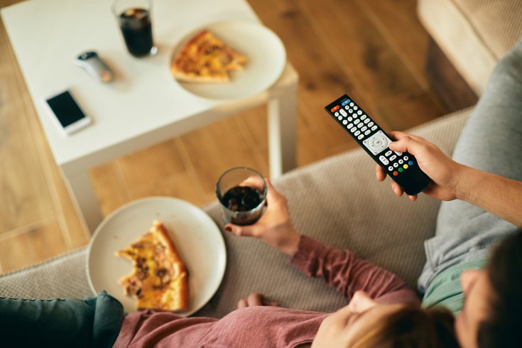 Purchased - Close-up of couple watching TV while eating pizza at home