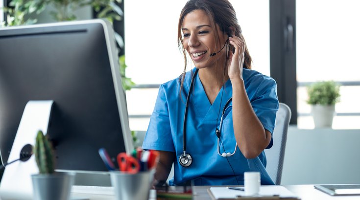 Purchased - Female doctor talking with earphone while explaining medical treatment to patient through a video call