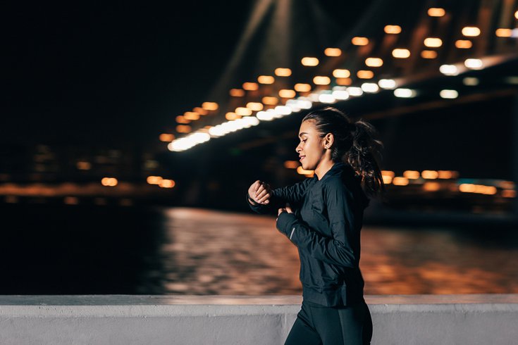Purchased - woman jogging at night looking at fitness tracker