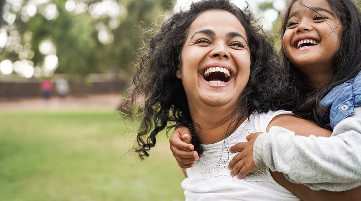 Purchased - Woman laughing while carrying her child