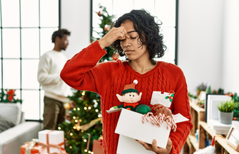 Purchased - woman standing by christmas tree with decoration tired