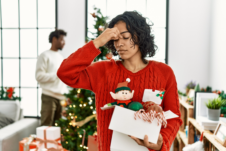 Purchased - woman standing by christmas tree with decoration tired