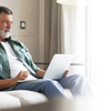 Purchased - Older man sitting on a sofa on laptop