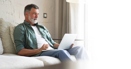 Purchased - Older man sitting on a sofa on laptop