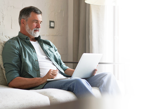 Purchased - Older man sitting on a sofa on laptop