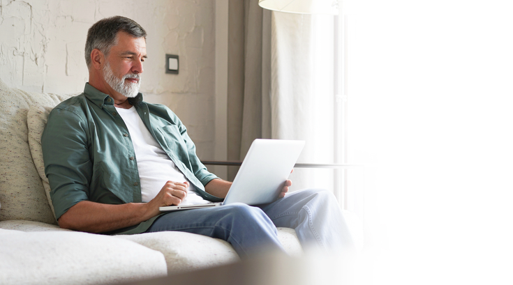 Purchased - Older man sitting on a sofa on laptop