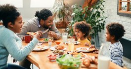 family enjoying in conversation while eating breakfast together at dining table