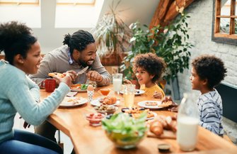 family enjoying in conversation while eating breakfast together at dining table