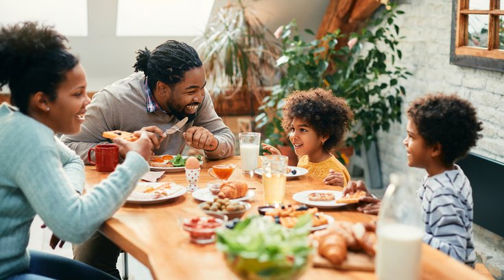 family enjoying in conversation while eating breakfast together at dining table