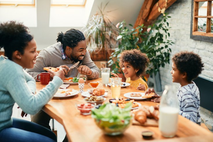 family enjoying in conversation while eating breakfast together at dining table