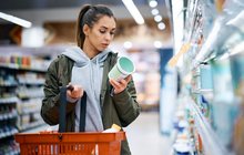 Purchased - woman reading nutrition label while buying diary product in supermarket
