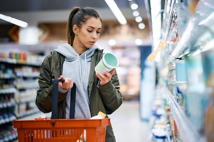 Purchased - woman reading nutrition label while buying diary product in supermarket