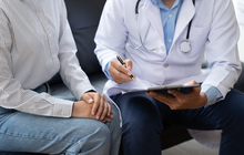 Purchased - Doctor and patient sitting and talking at medical examination at hospital office, close-up