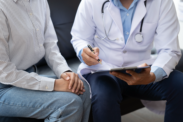 Purchased - Doctor and patient sitting and talking at medical examination at hospital office, close-up