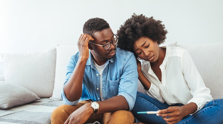 Purchased - A disappointed couple looking at the results of a pregnancy test