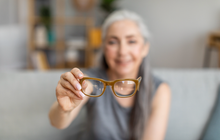 Purchased - elderly gray-haired female holding glasses in living room