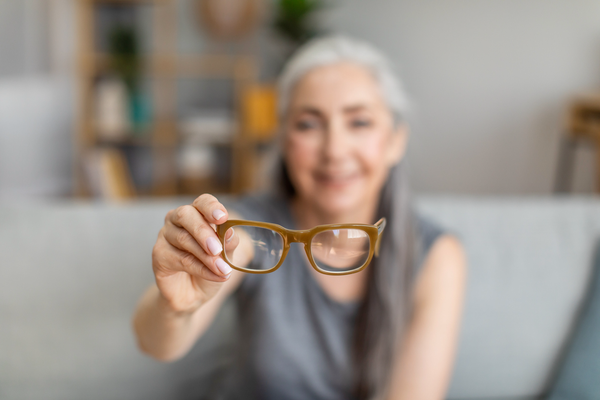 Purchased - elderly gray-haired female holding glasses in living room