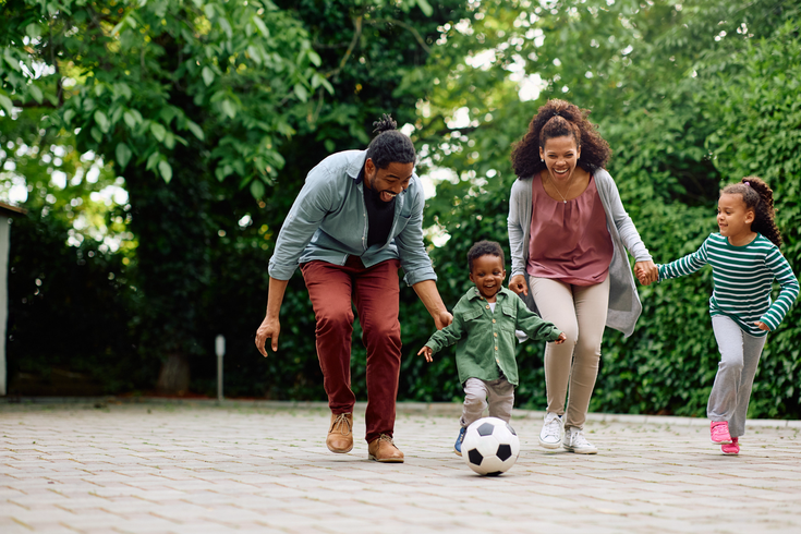Purchaed - Happy parents and their kids playing with soccer ball in the park
