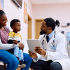 Purchased - doctor using touchpad while talking to mother and her son in waiting room