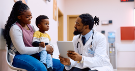 Purchased - doctor using touchpad while talking to mother and her son in waiting room