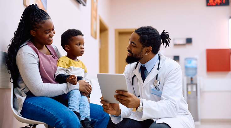 Purchased - doctor using touchpad while talking to mother and her son in waiting room