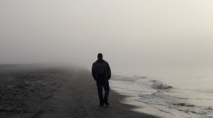 Man walking alone on a foggy beach