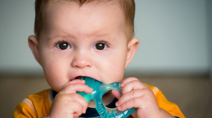 Baby chewing on teething ring stock photo
