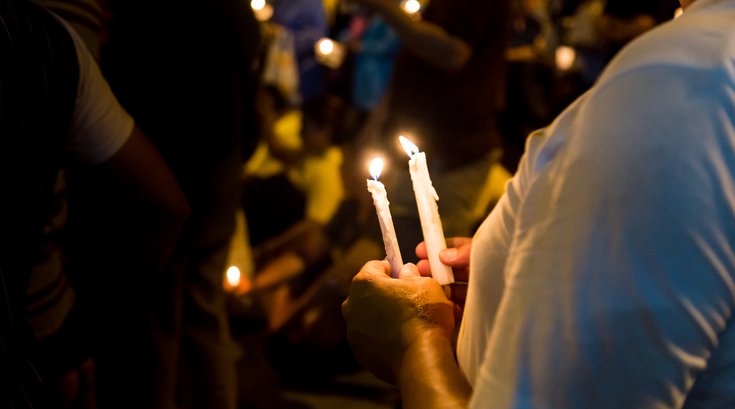 Purchased - People hold candles at a vigil