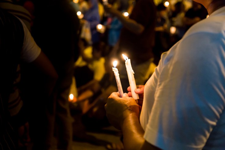 Purchased - People hold candles at a vigil