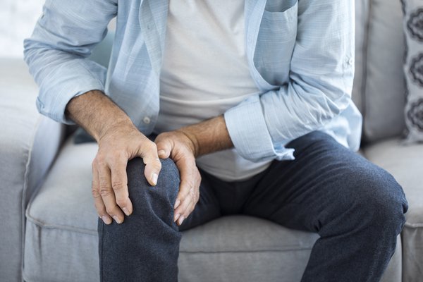 Purchased - Older person holding their knee in pain