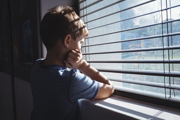 Purchased - Boy looking through window glass of school
