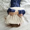 Woman in bed with a pillow over her head