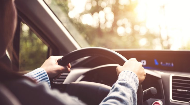Purchased - Woman driving a car while sunny
