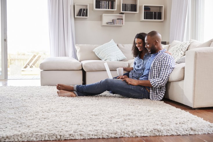 Purchased - Young couple looking at laptop sitting on floor