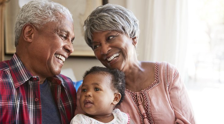Purchased - Grandparents Sitting On Sofa With Baby Granddaughter At Home